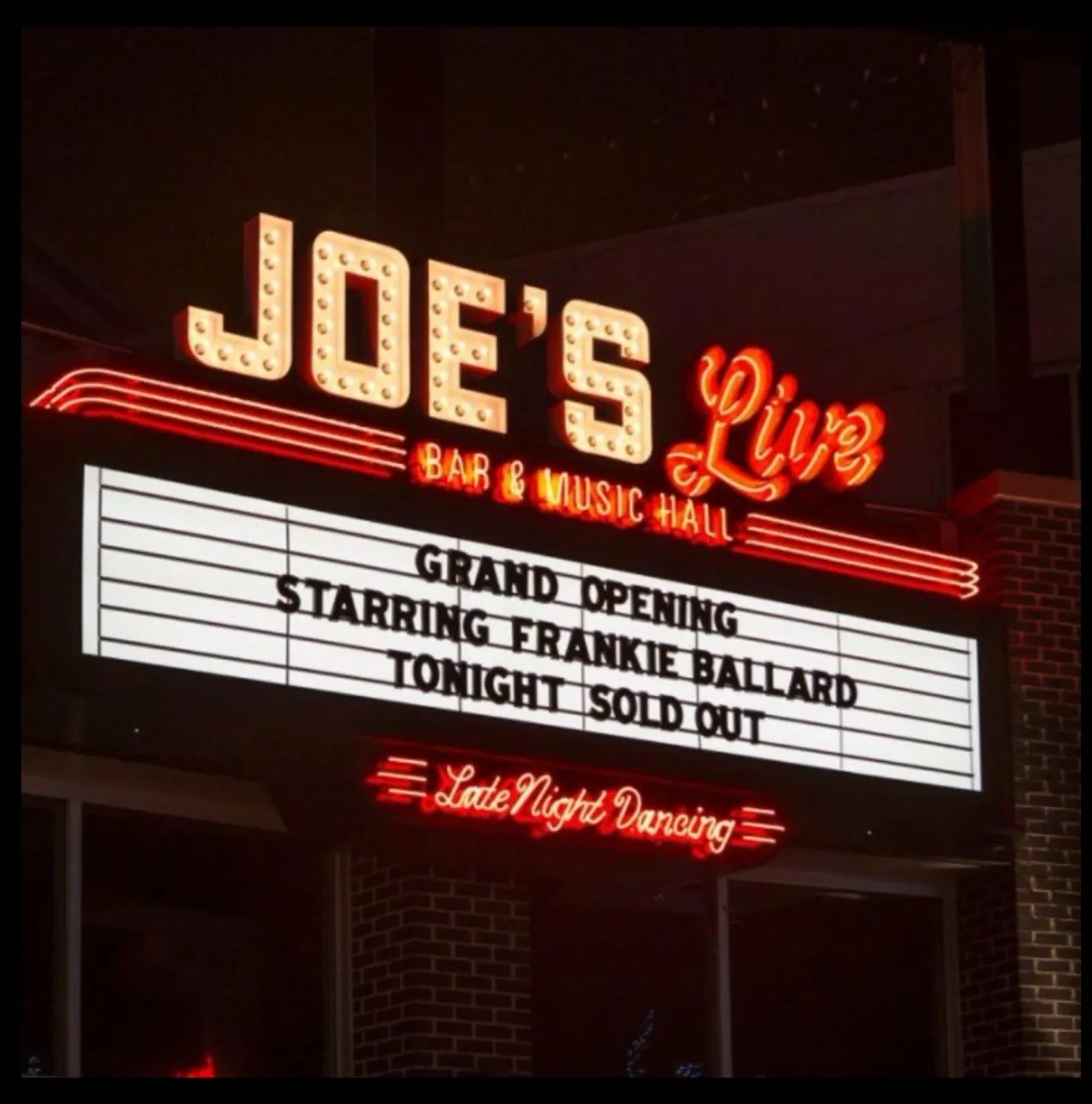Marquee with open-face exposed-neon channel letters and bulb border, lit at night